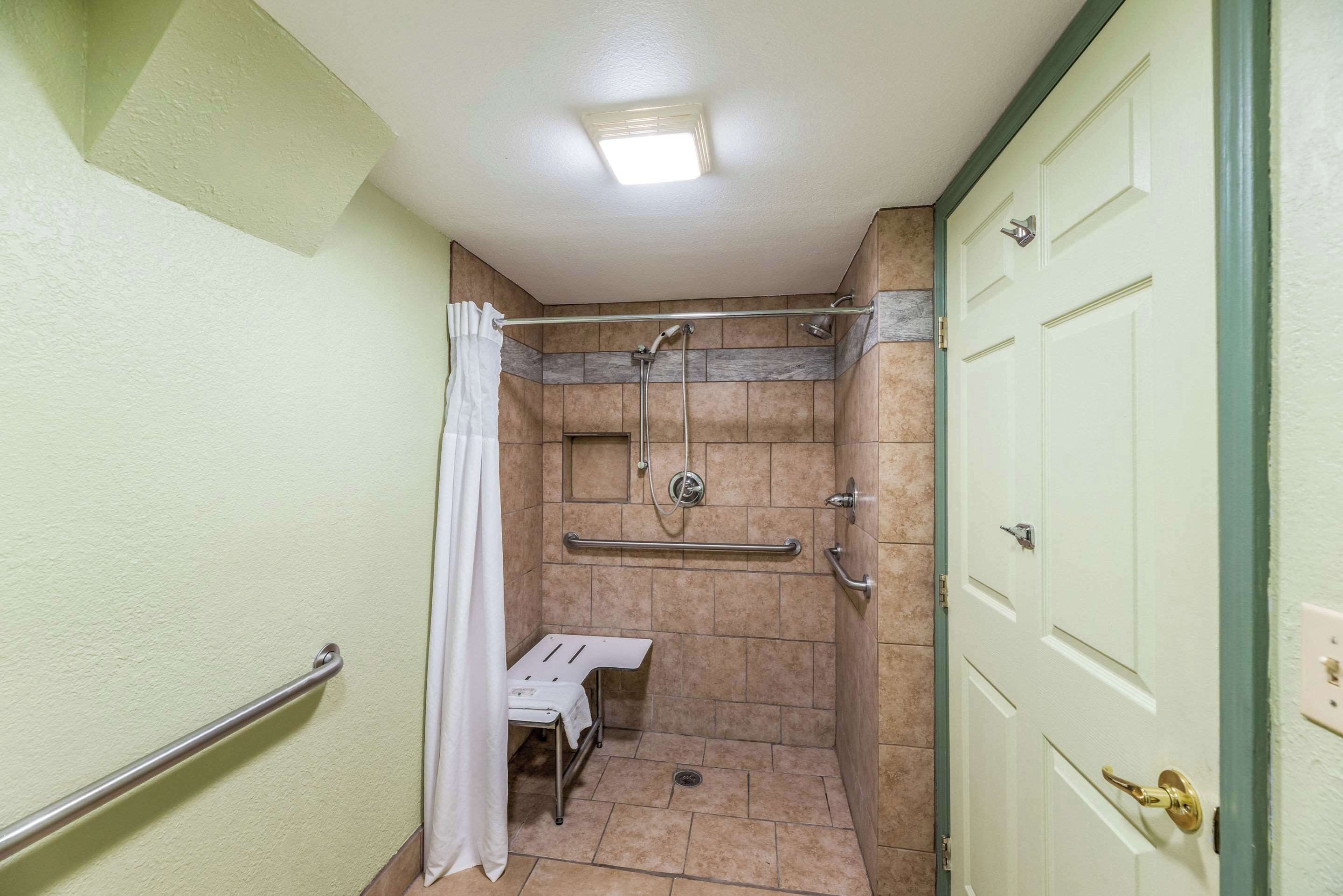 Zona de bany petita i tancada, amb seient, barres de sujeció i porta.