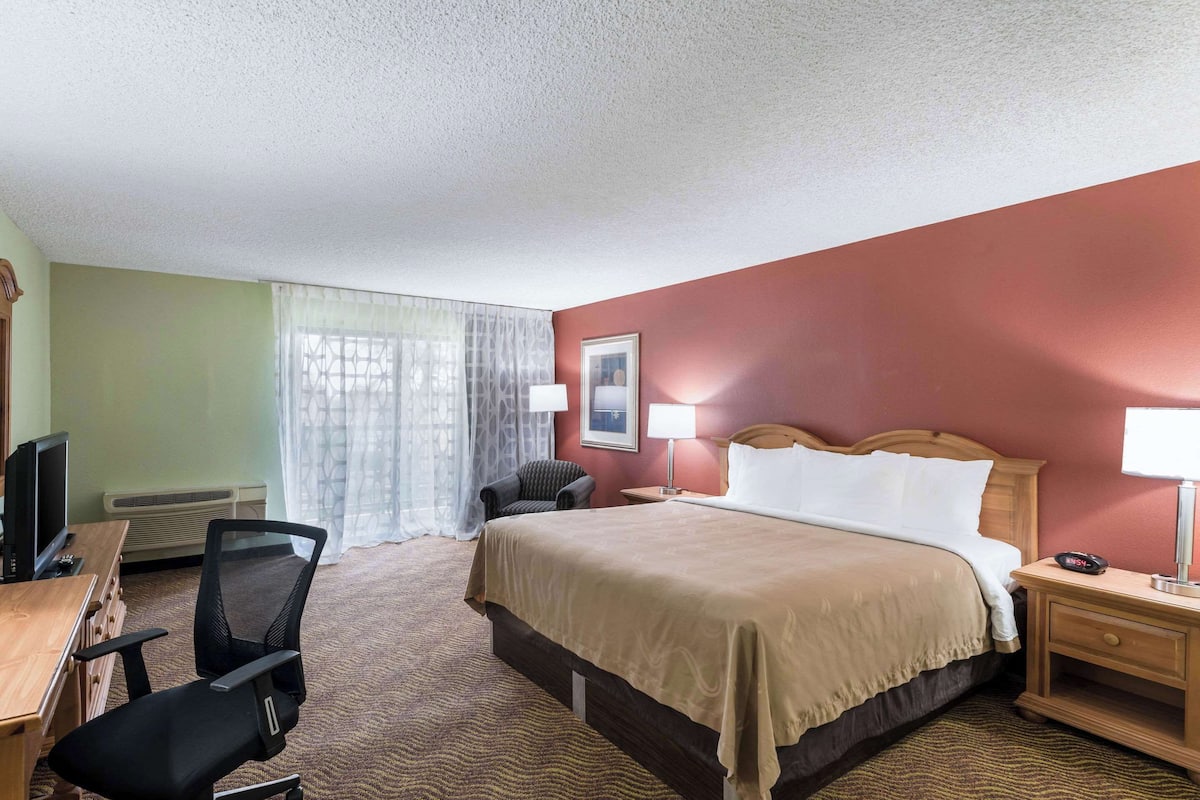A hotel room with a bed, desk, chair, and two bedside lamps.