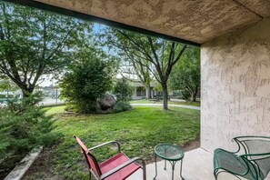 A covered outdoor area with a red chair, a green chair, and a small table.