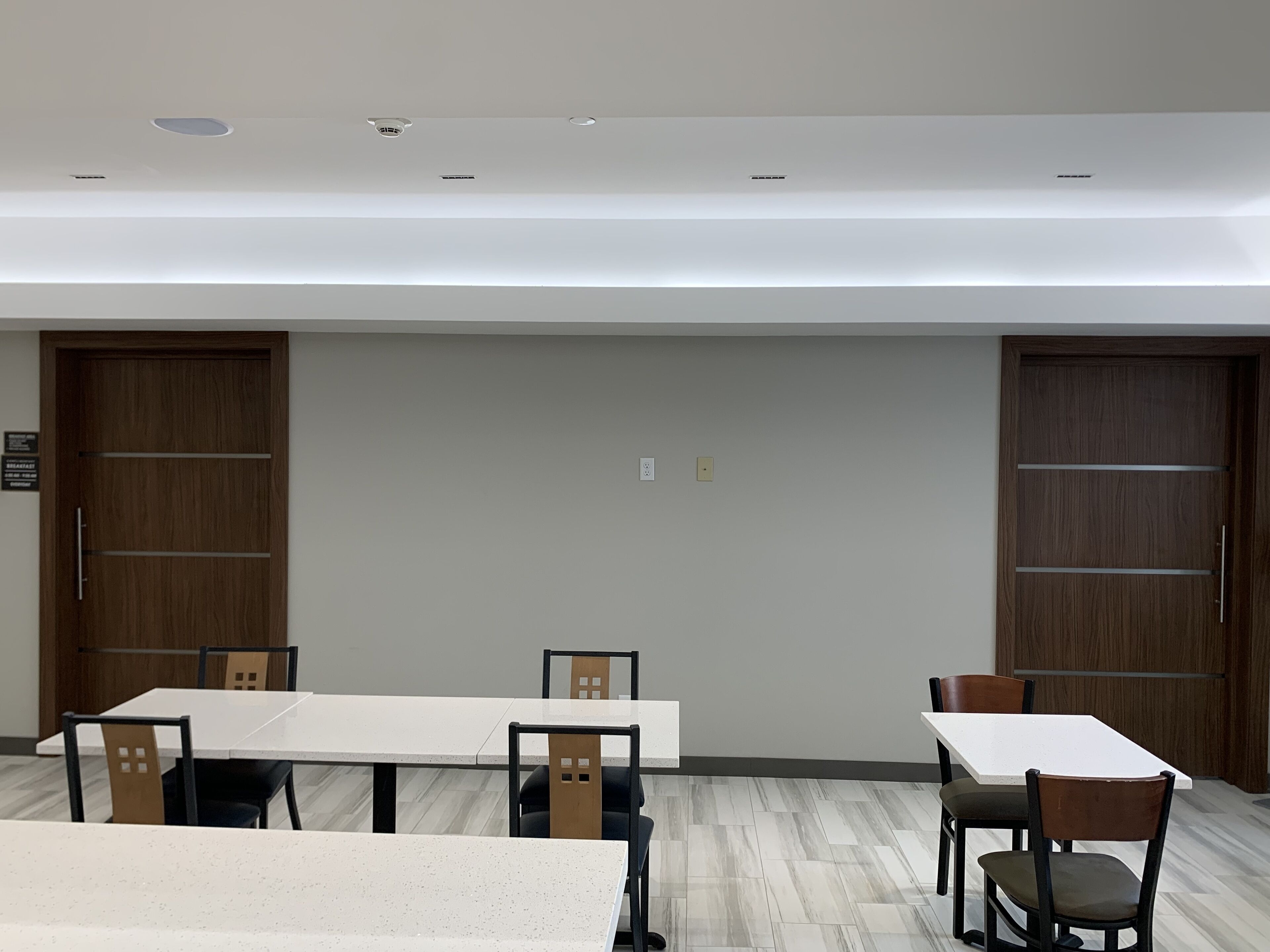 Un salón de conferencias con una larga mesa, sillas y dos puertas de madera.