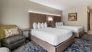 Une chambre d’hôtel avec un grand lit, un canapé, une table de chevet et une lampe.