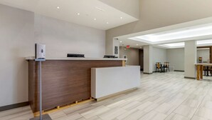 Un espace d’accueil moderne avec un comptoir de réception en bois, un comptoir blanc et un sol carrelé.