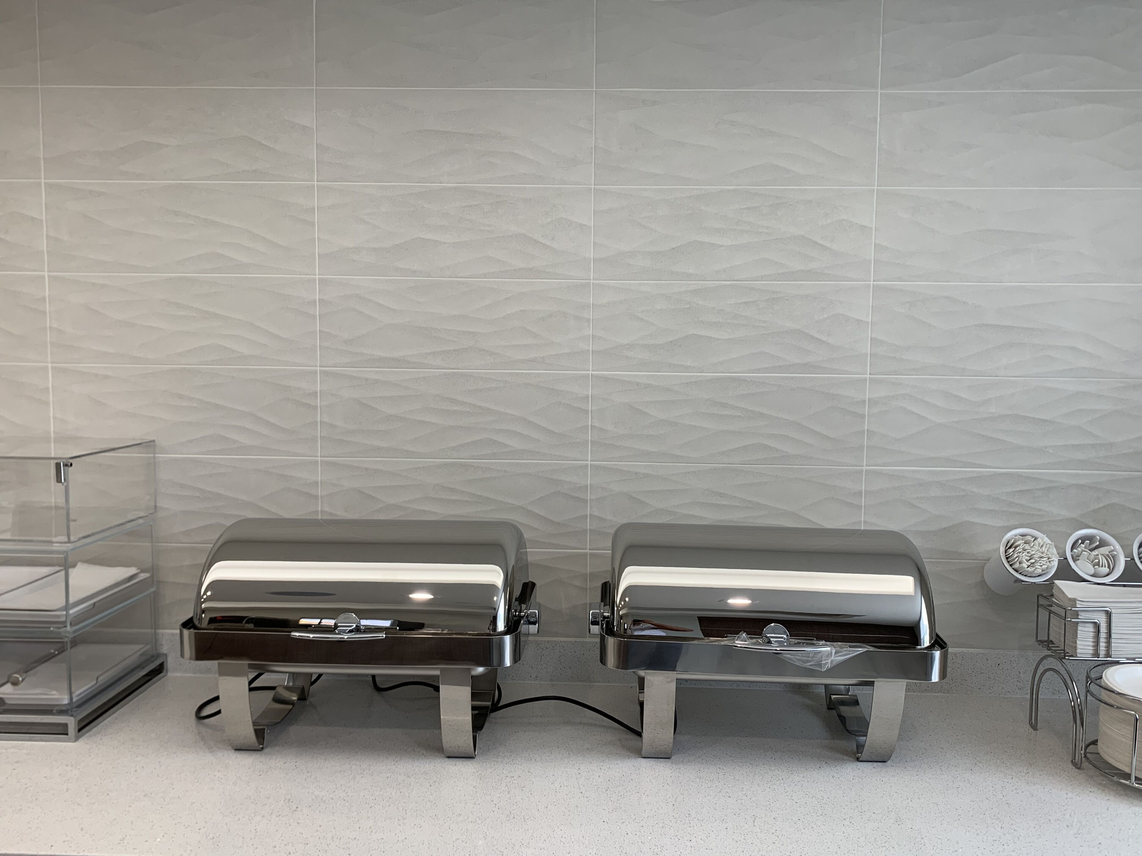 Two stainless steel barbecue grills with a modern design, placed on a countertop with a speckled surface.