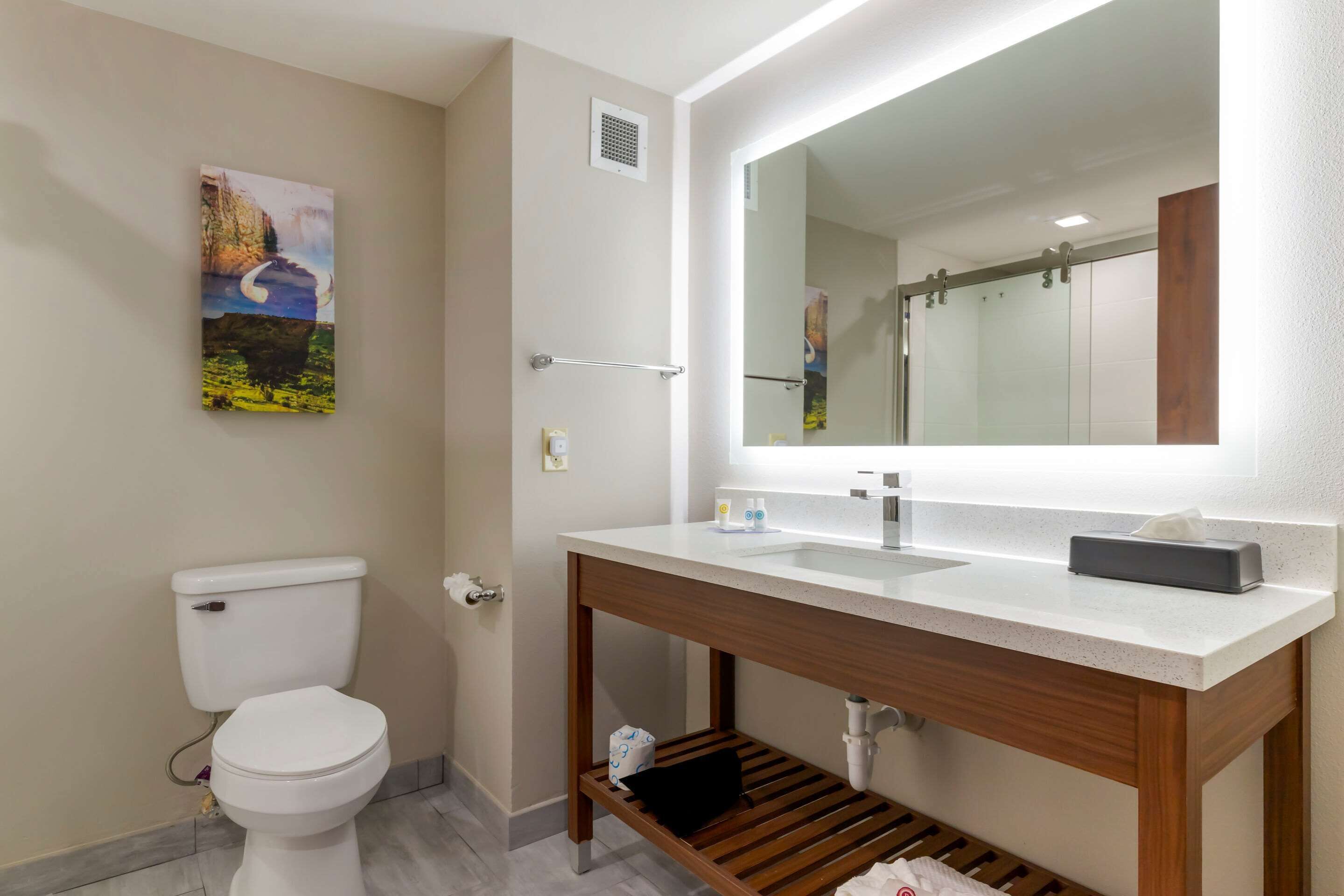 Een moderne badkamer met toilet, wastafel en spiegel.