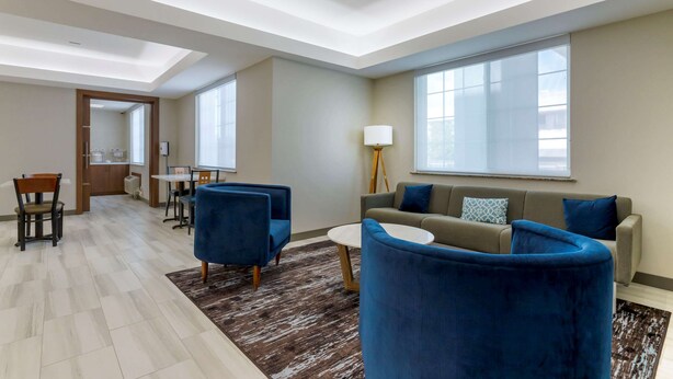 Un salon moderne comprenant un canapé, deux fauteuils, une table basse et un coin repas avec des chaises et une table.