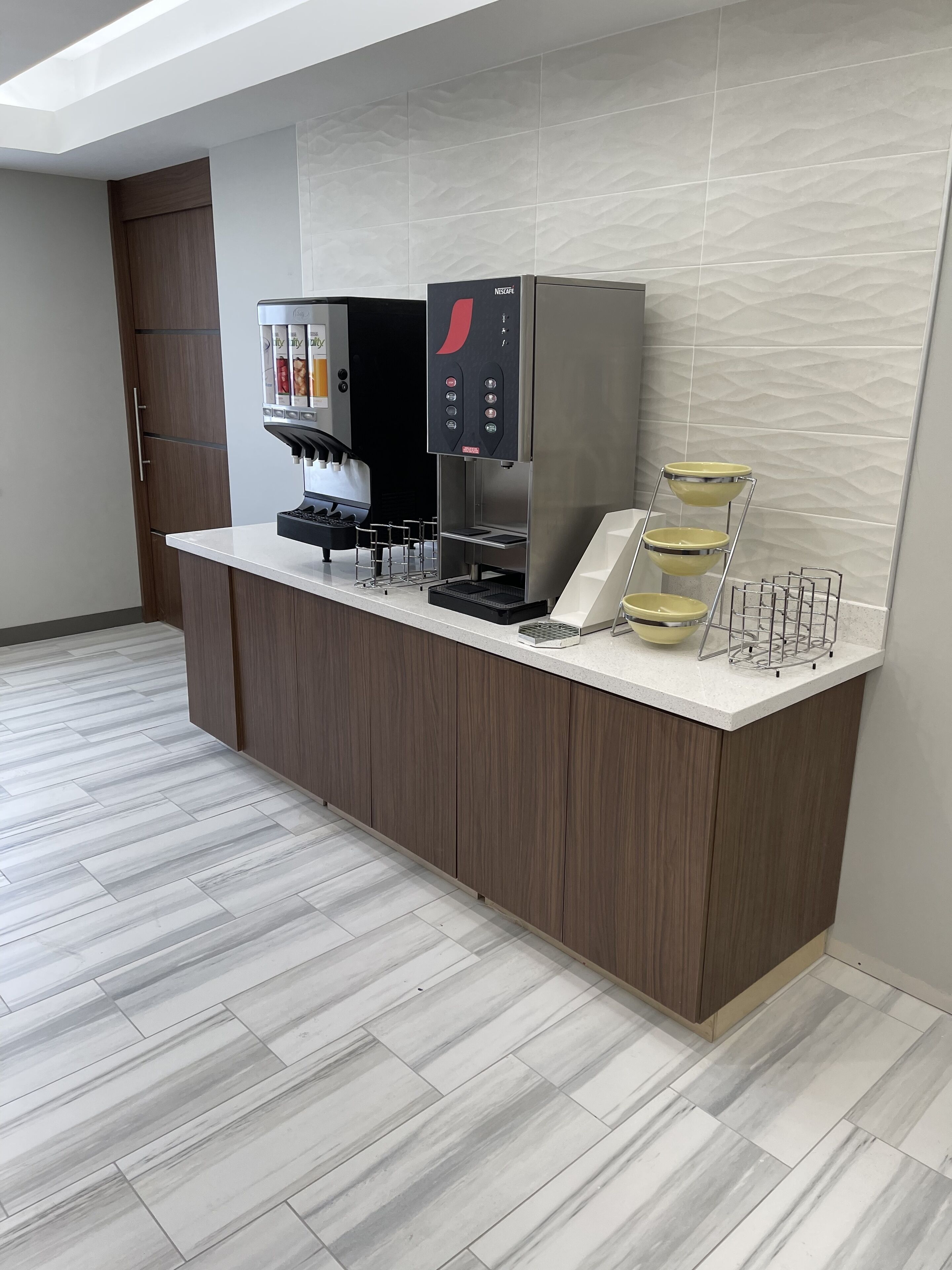 A modern kitchen area with a coffee machine, a microwave, and a small sink.