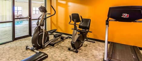Un gimnasio con equipo de ejercicio, incluyendo cinta de correr, elíptica y bicicleta estática.