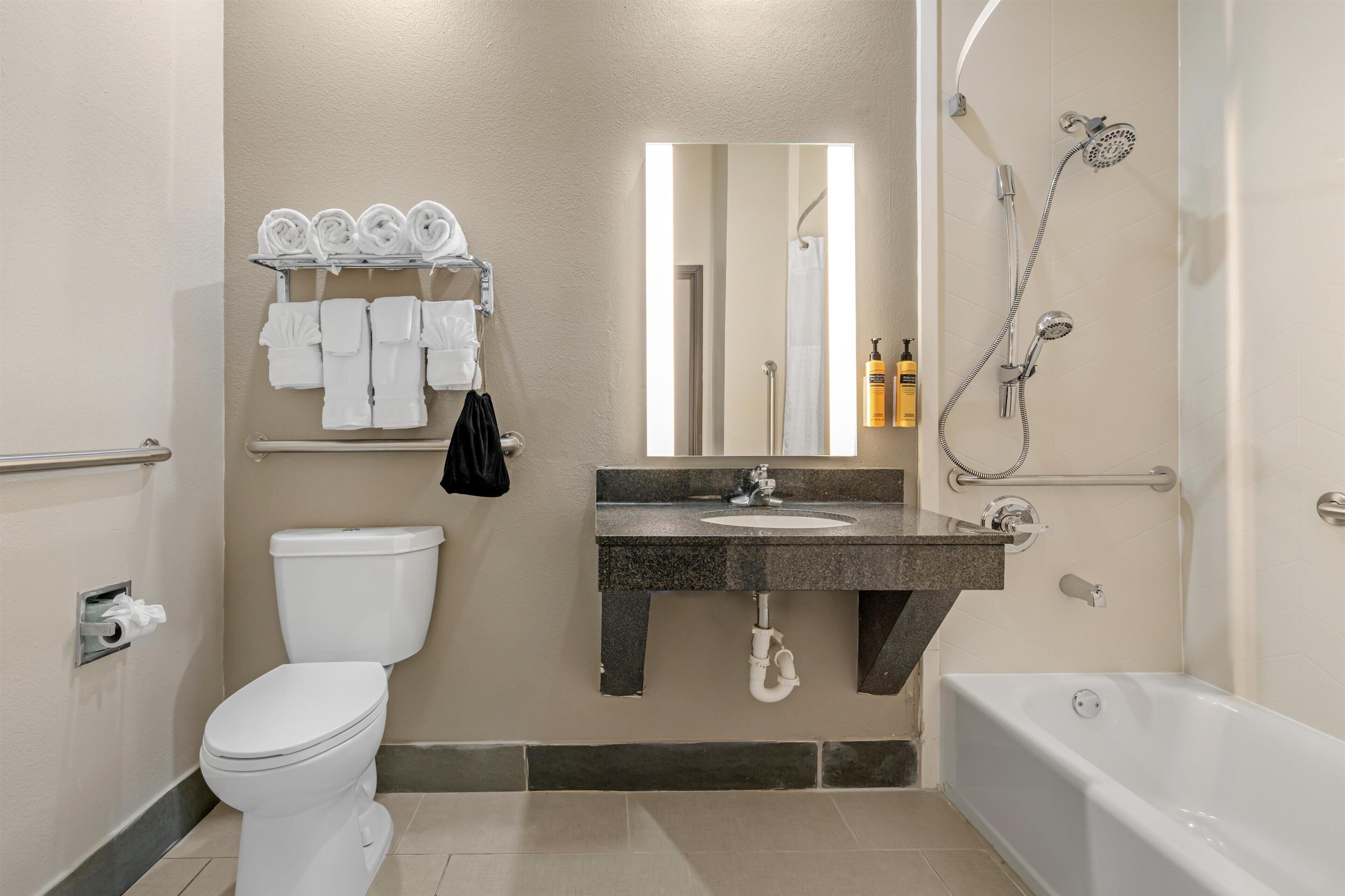 A bathroom with a toilet, sink, mirror, towel rack, shower, and bathtub.