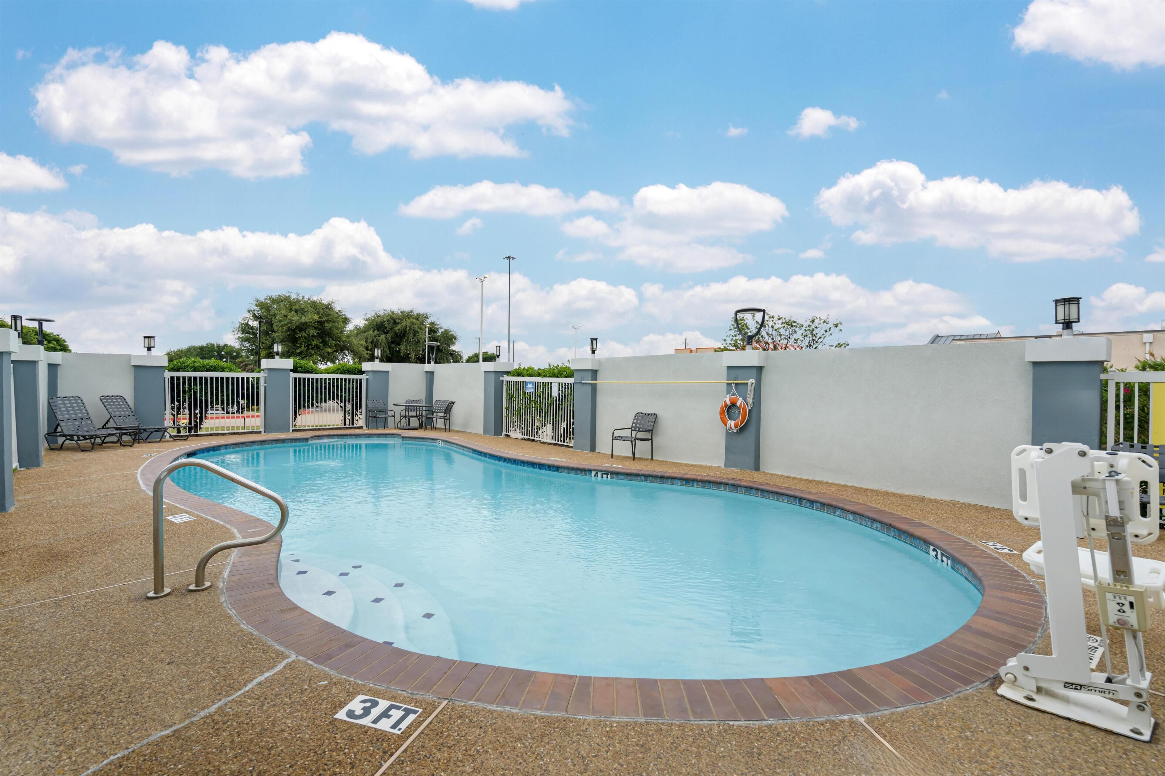 Une piscine équipée d’une bouée de sauvetage, de chaises longues et surplombée d’un ciel dégagé.