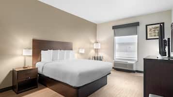 A hotel room with a bed, bedside tables, lamps, a desk, and a large window.