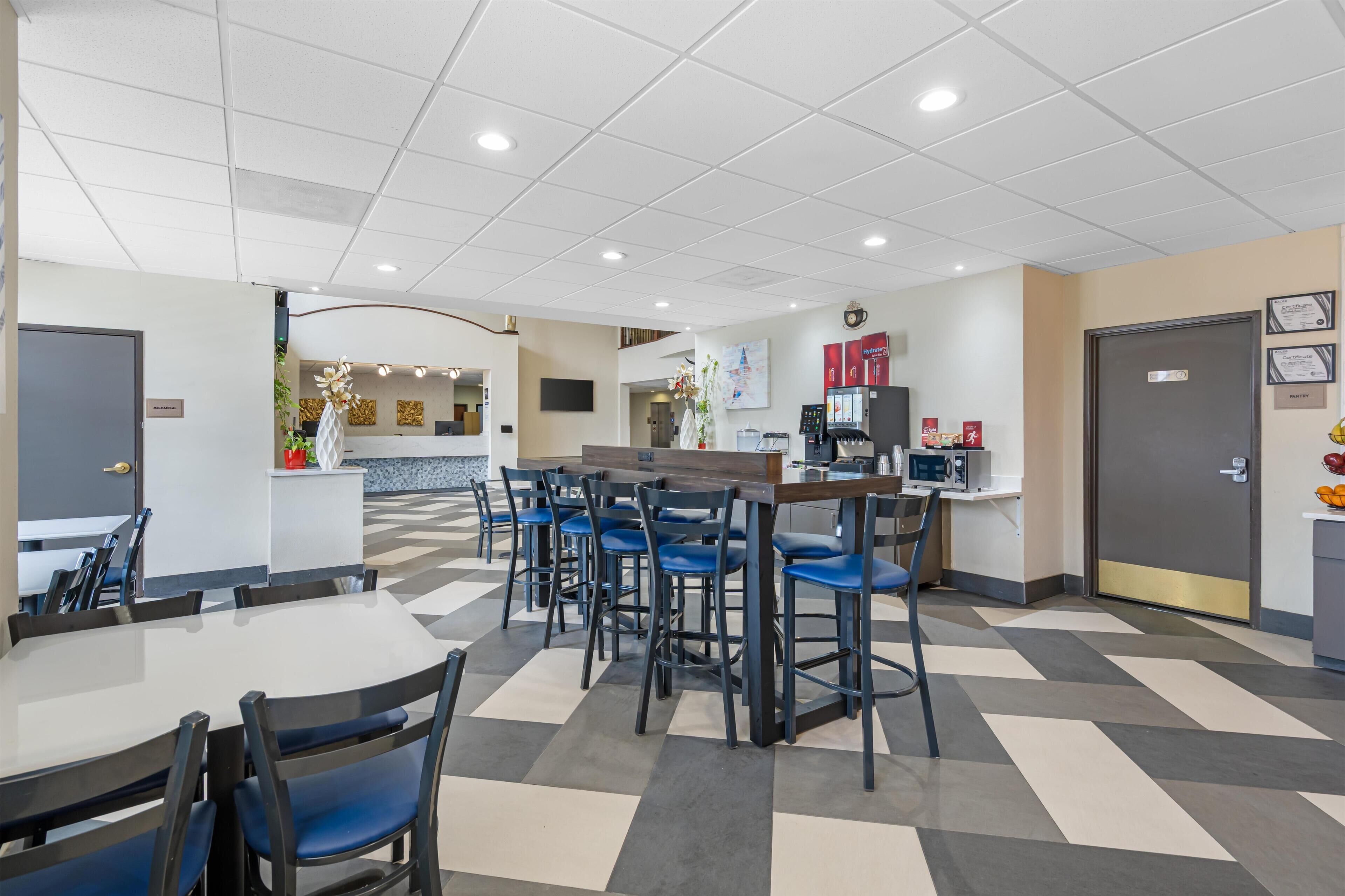Un espace de restauration intérieur moderne, avec un sol à carreaux, un bar central et des chaises bleues.