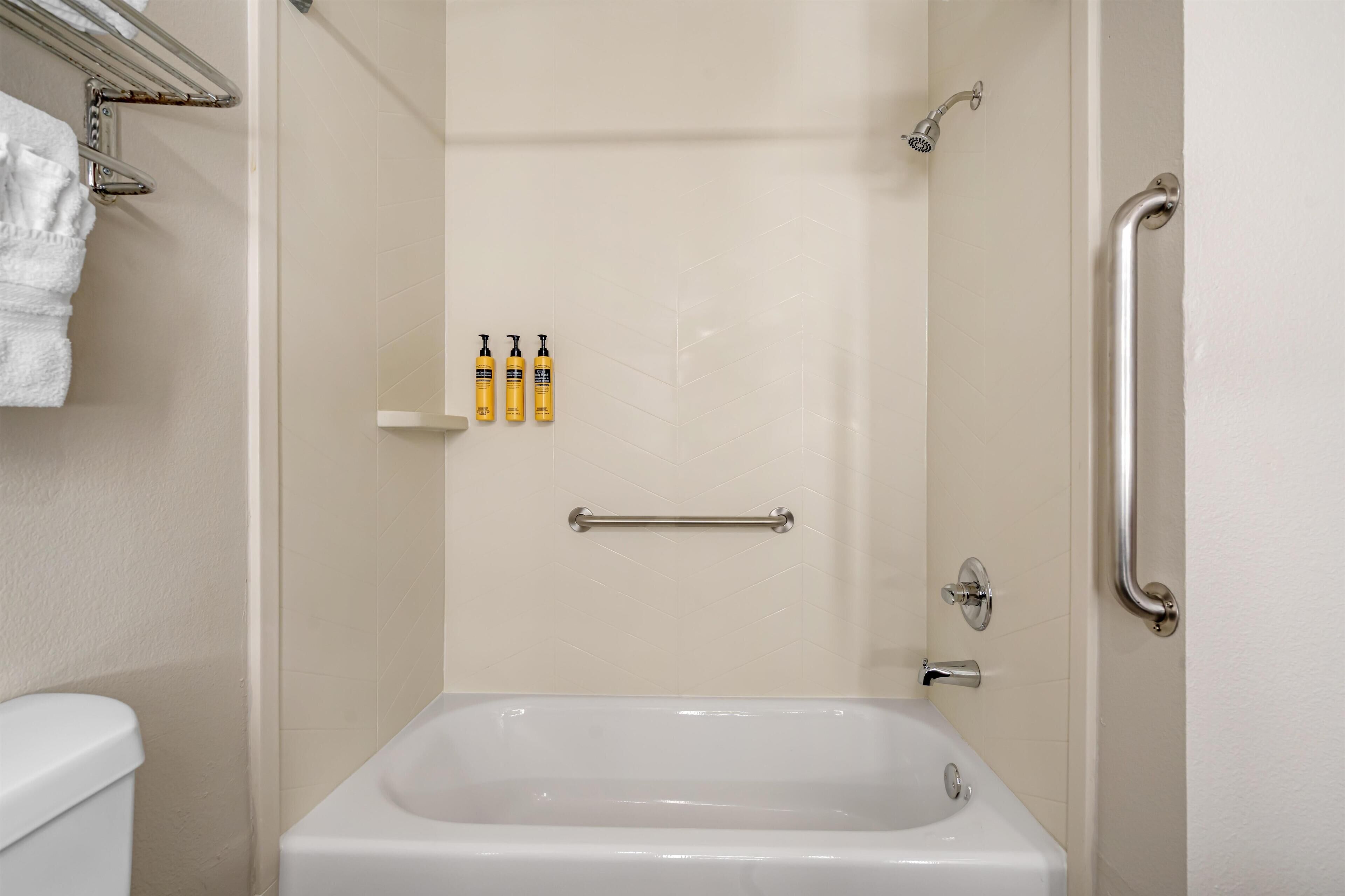 A bathroom with a bathtub, a shower, a toilet, and a towel rack.