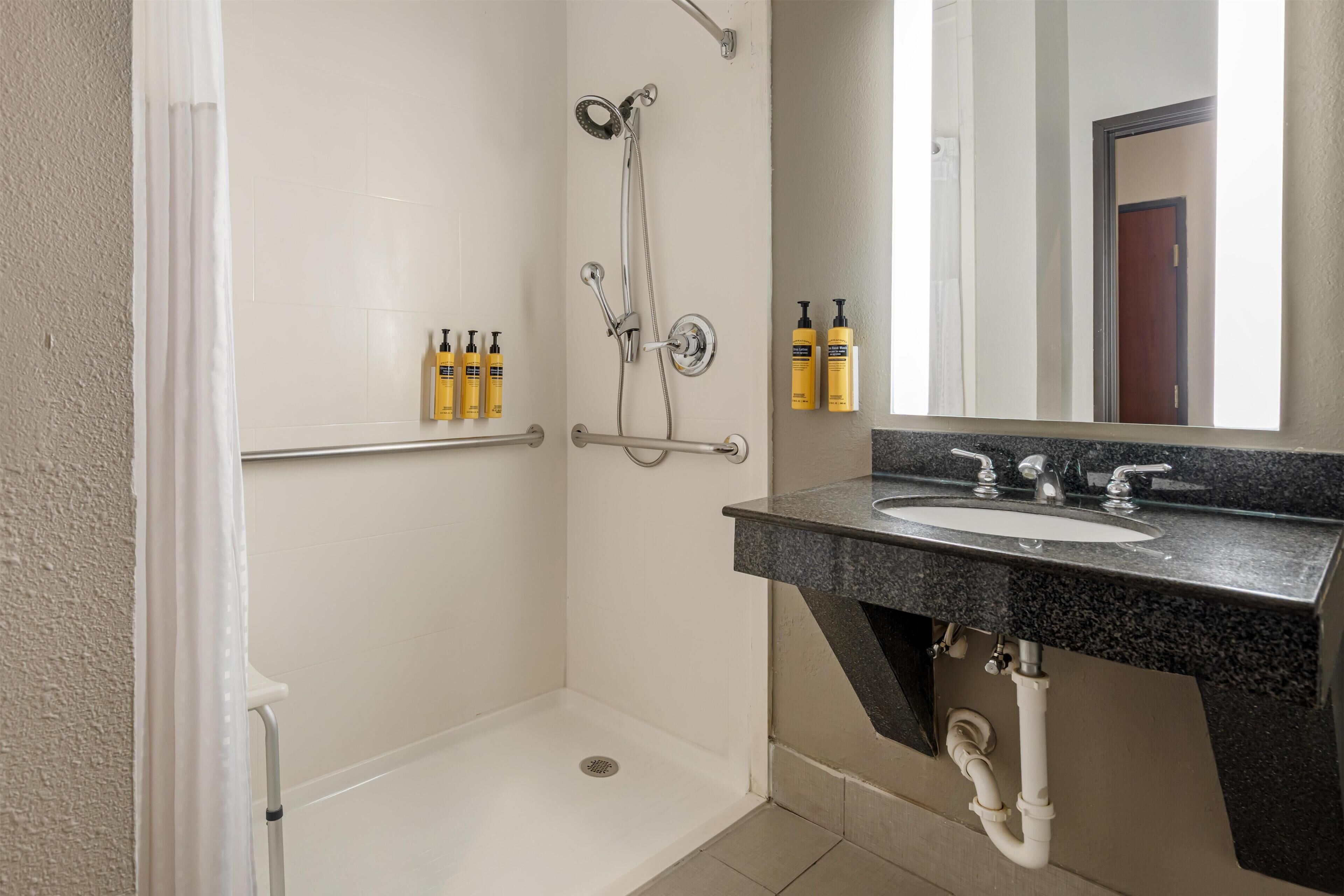 A bathroom with a shower, a sink, and toiletries on the wall.