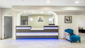 A reception area with a modern design, featuring a reception desk, a blue chair, and a framed artwork on the wall. - Quality Inn & Suites Rio Grande City (Rio Grande City)