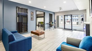 A modern lobby with blue sofas, a wooden coffee table, and a view of the street through large glass doors. - Quality Inn & Suites Rio Grande City (Rio Grande City)