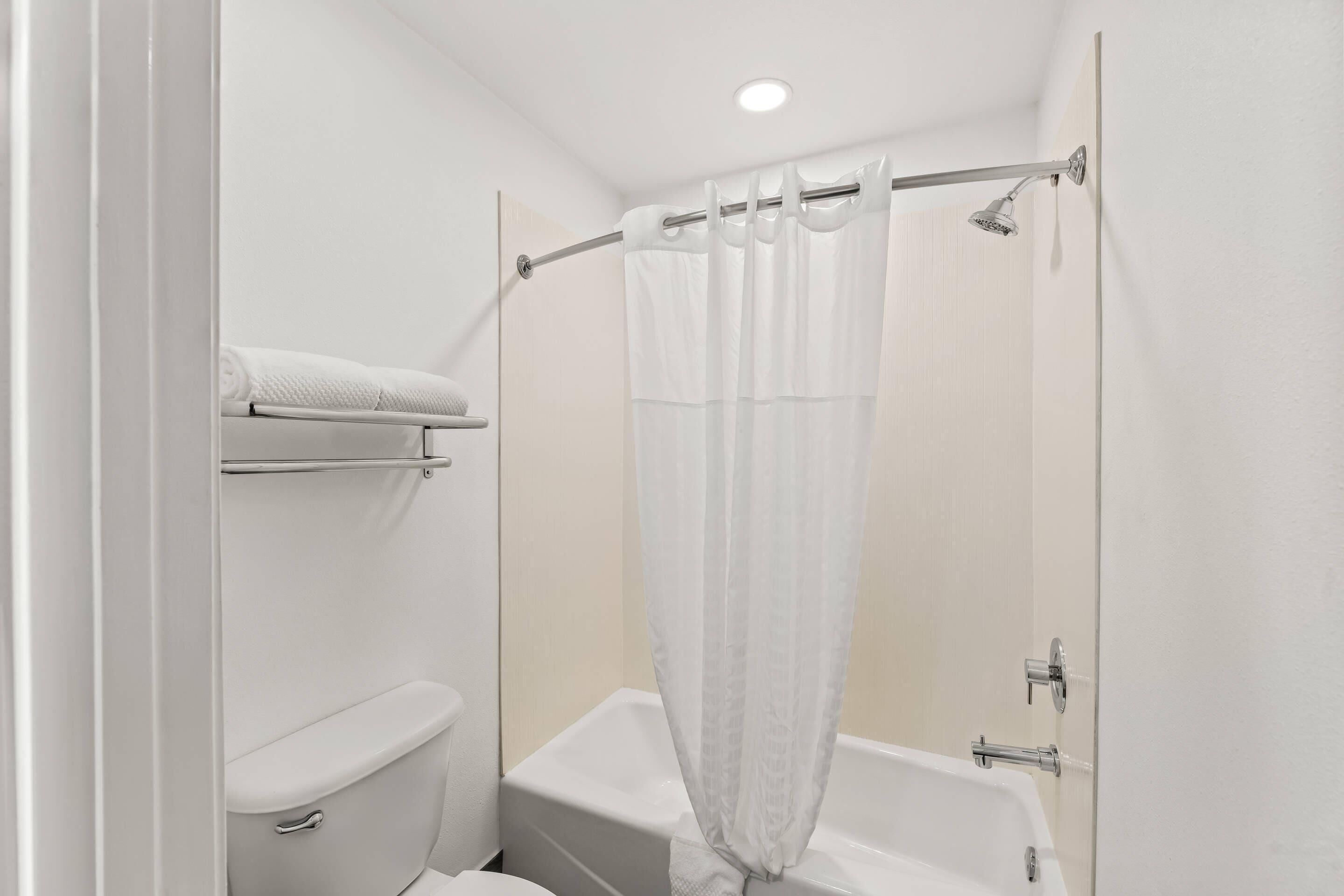 A small, modern bathroom with a toilet, a bathtub, and a shower curtain.
