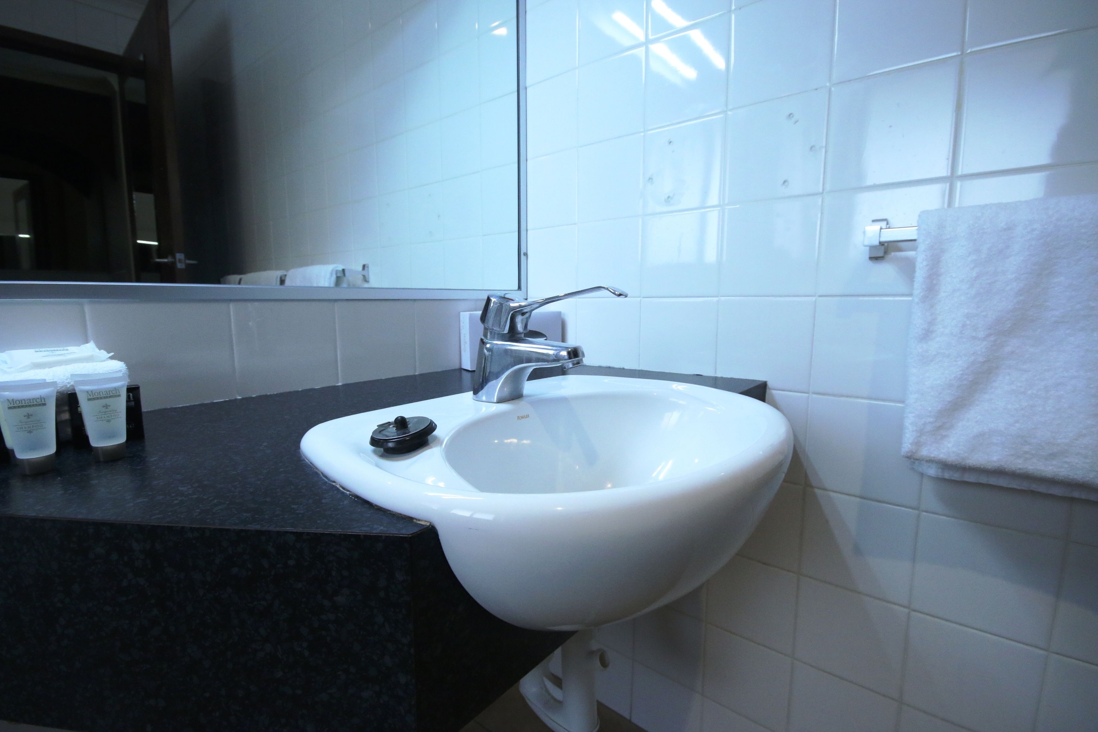 A bathroom with a white sink, a mirror, and a towel hanging on the wall.
