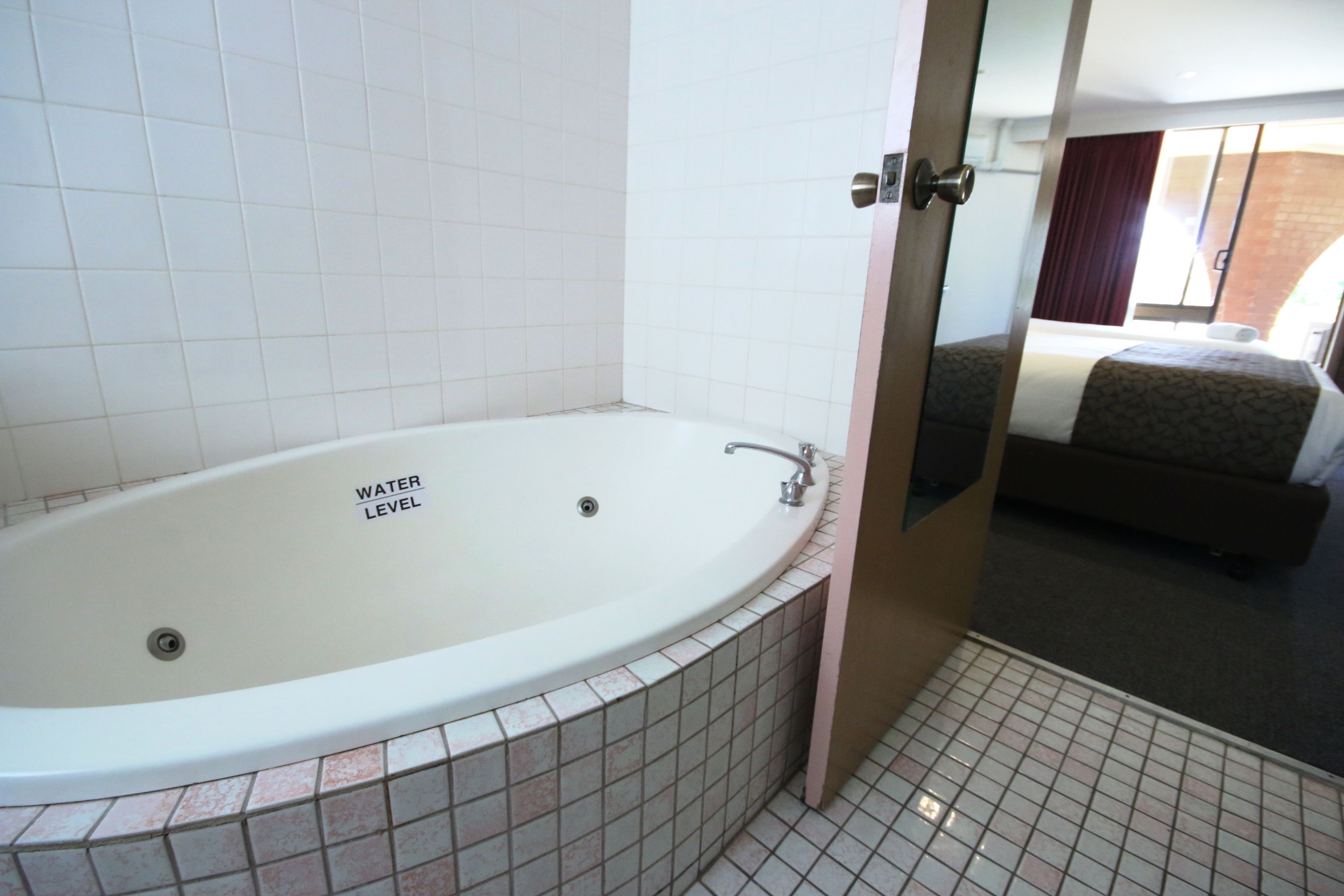 Un baño con bañera, paredes de azulejos e indicador de nivel de agua visible.