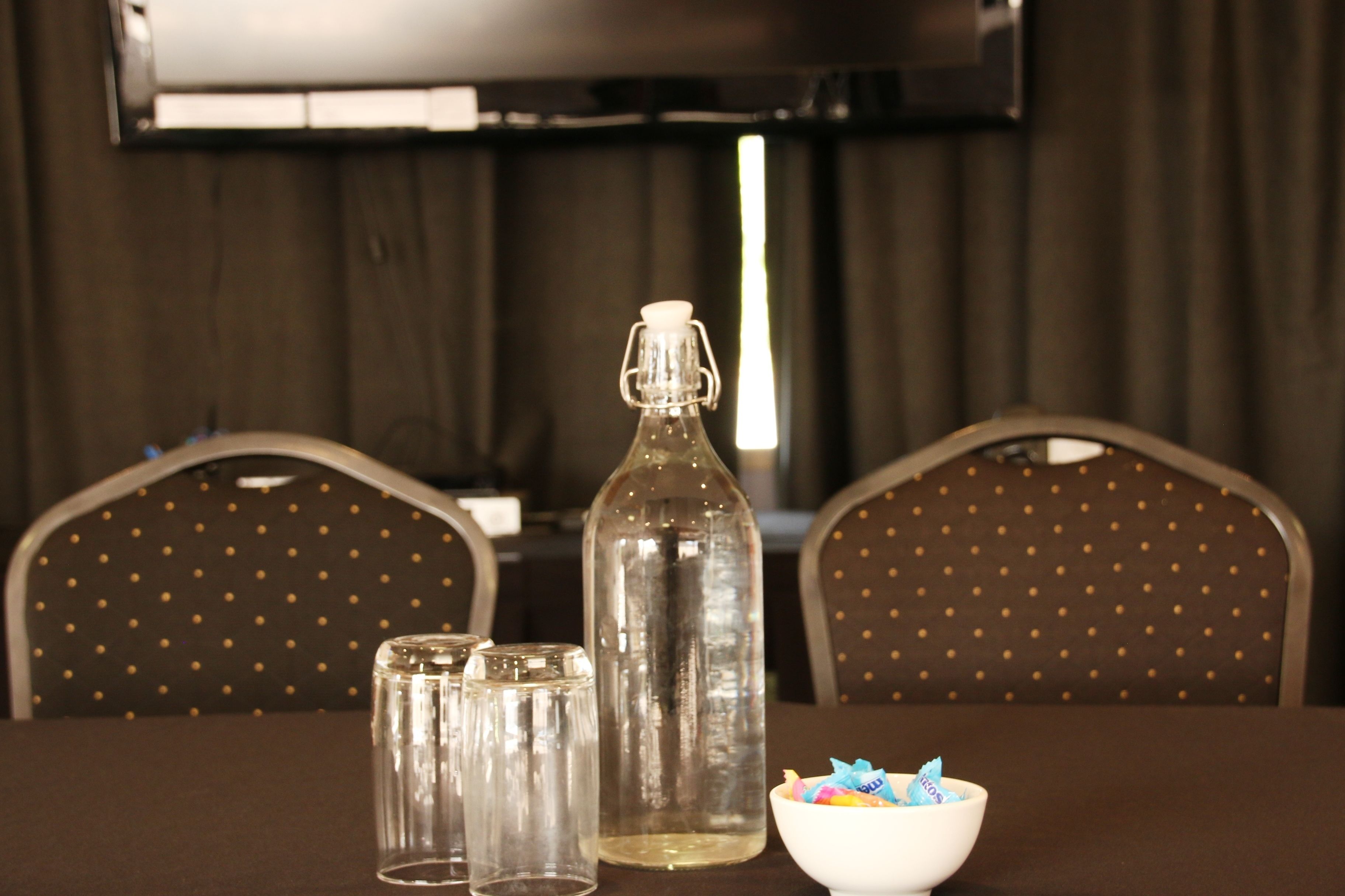 A table with a bottle, salt and pepper shakers, and a bowl of colorful items.