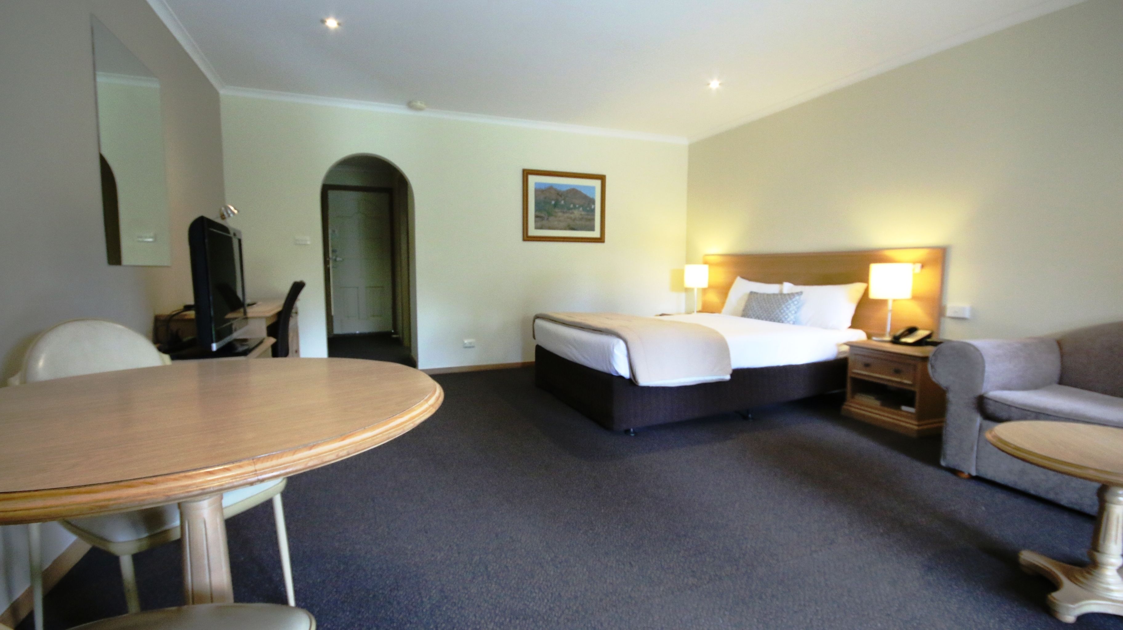 Une chambre d’hôtel équipée d’un lit, d’un bureau, d’une chaise, d’un canapé et d’une télévision.