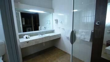 A modern bathroom with a glass shower door, a white sink, and a large mirror.