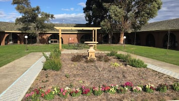 Stroll through the serene courtyard, surrounded by a vibrant garden and a decorative stone centerpiece.
