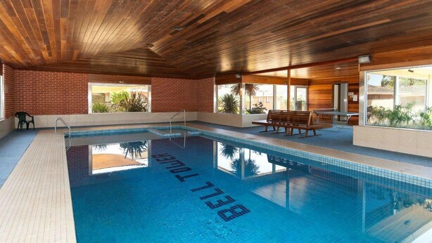 An indoor swimming pool with a wooden ceiling and brick walls. - Bell Tower Inn (Alfredton)