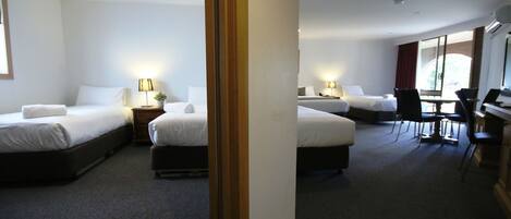 A hotel room with three beds, a desk, and a chair.