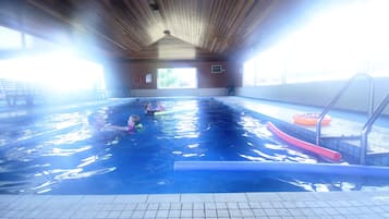 An indoor swimming pool with a wooden ceiling and tiled floor.