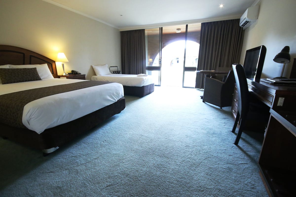 A hotel room with two beds, a desk, a chair, and a TV.