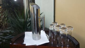 A metallic pitcher on a wooden table with a white napkin, surrounded by clear glass jars.