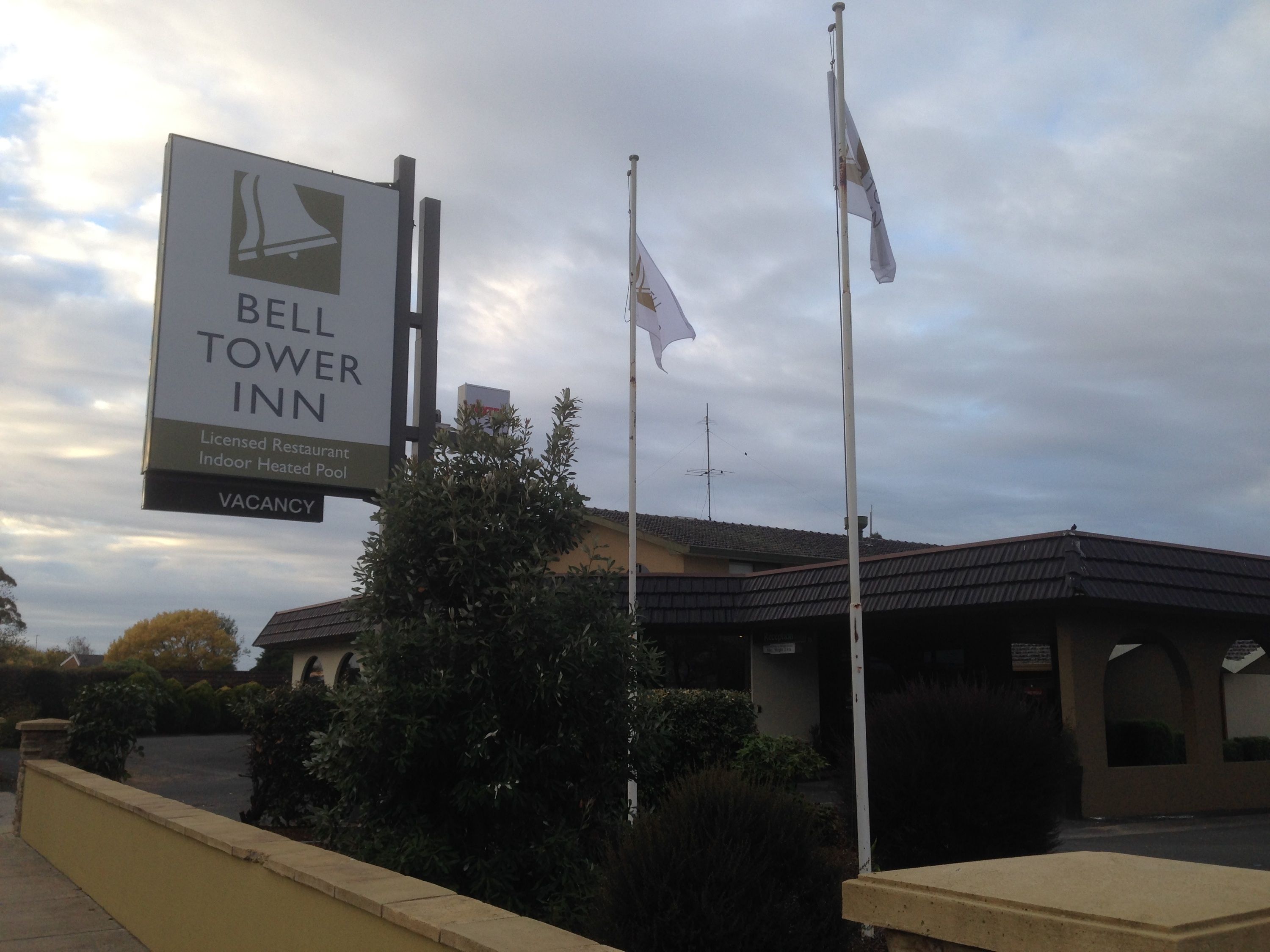 A sign for Bell Tower Inn, indicating it is a licensed restaurant with an indoor heated pool and a vacancy.
