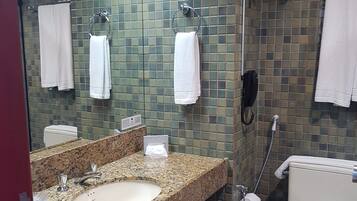 Un baño con lavamanos de granito, dos toalleros, un inodoro y una zona de ducha.