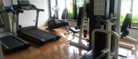 Un gimnasio con cintas de correr, elípticas y máquinas de pesas.