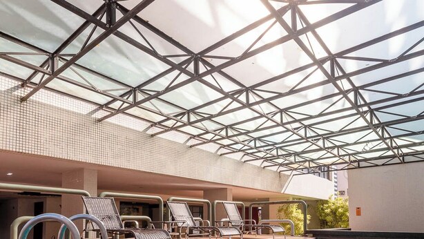 An indoor swimming pool with a glass ceiling, lounge chairs, and a tiled floor. - Rede Andrade LG Inn (Recife)