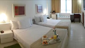A hotel room with two beds, a desk, and a small table with a tray of breakfast items. - Rede Andrade LG Inn (Recife)