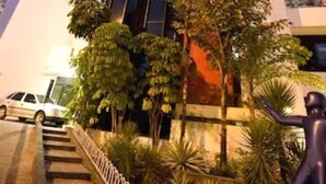 A tall building with a red and white facade, surrounded by greenery and a staircase leading to the entrance. - Rede Andrade LG Inn (Recife)