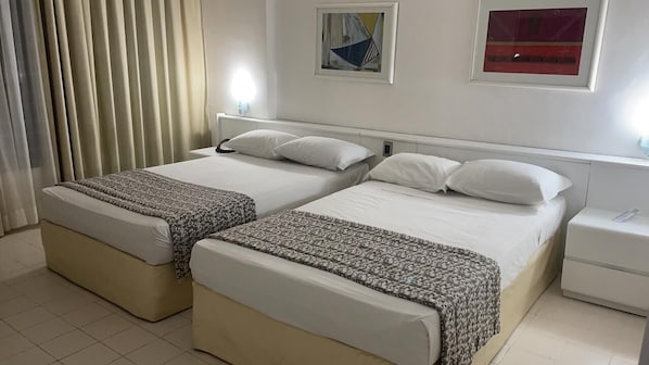 A hotel room with two beds, a bedside table, and a nightstand.