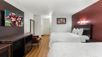 A hotel room with a bed, a desk, a chair, a dresser, and a mirror.