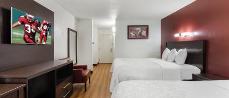 A hotel room with a bed, a desk, a chair, a dresser, and a mirror.
