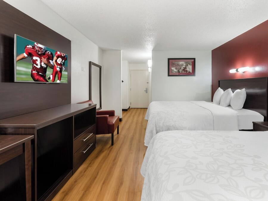 A hotel room with a bed, a desk, a chair, a dresser, and a mirror.