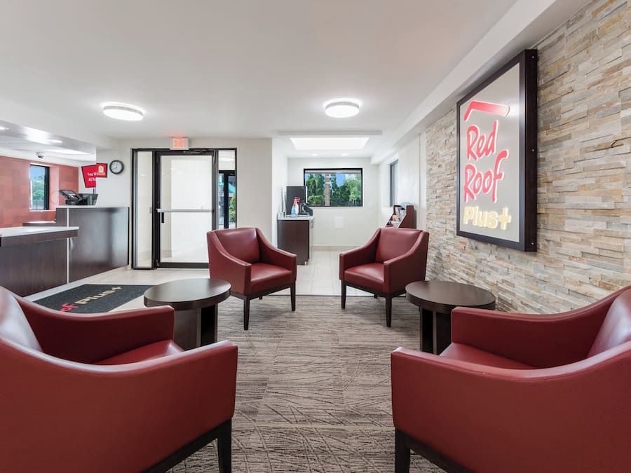 A reception area with a desk, chairs, a clock, and a wall-mounted sign.