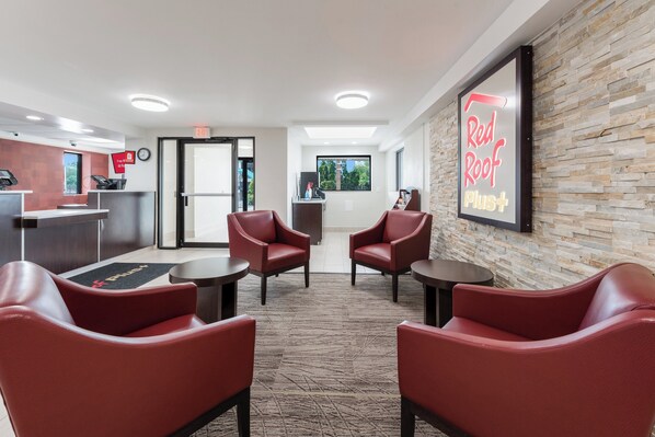 A reception area with a desk, chairs, a clock, and a wall-mounted sign.
