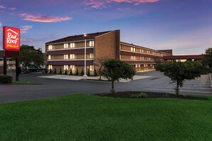 A multi-story hotel with a flat roof, a parking lot, and a sign for Red Roof Plus. - Red Roof Inn PLUS+ Columbus - Worthington (Columbus)
