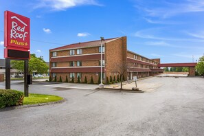 A Red Roof Plus hotel with a brick facade, multiple floors, and a parking lot.