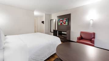 A hotel room with a bed, a desk, a chair, and a TV mounted on the wall.