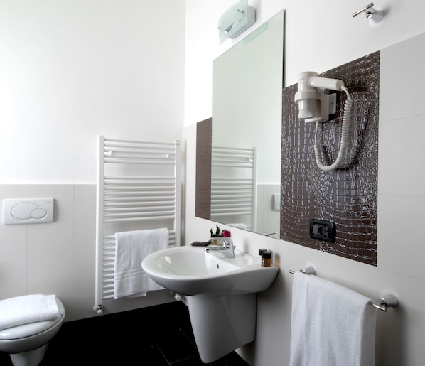A modern bathroom with a white sink, a mirror, a towel rack, and a towel hanging on the wall. - Hotel Villa Pannonia (Venice)