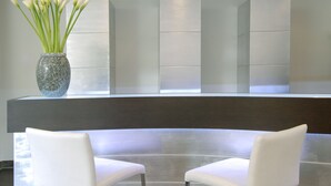 A reception desk with a vase of white flowers, two white chairs, and a modern, minimalist design. - Hotel Villa Pannonia (Venice)