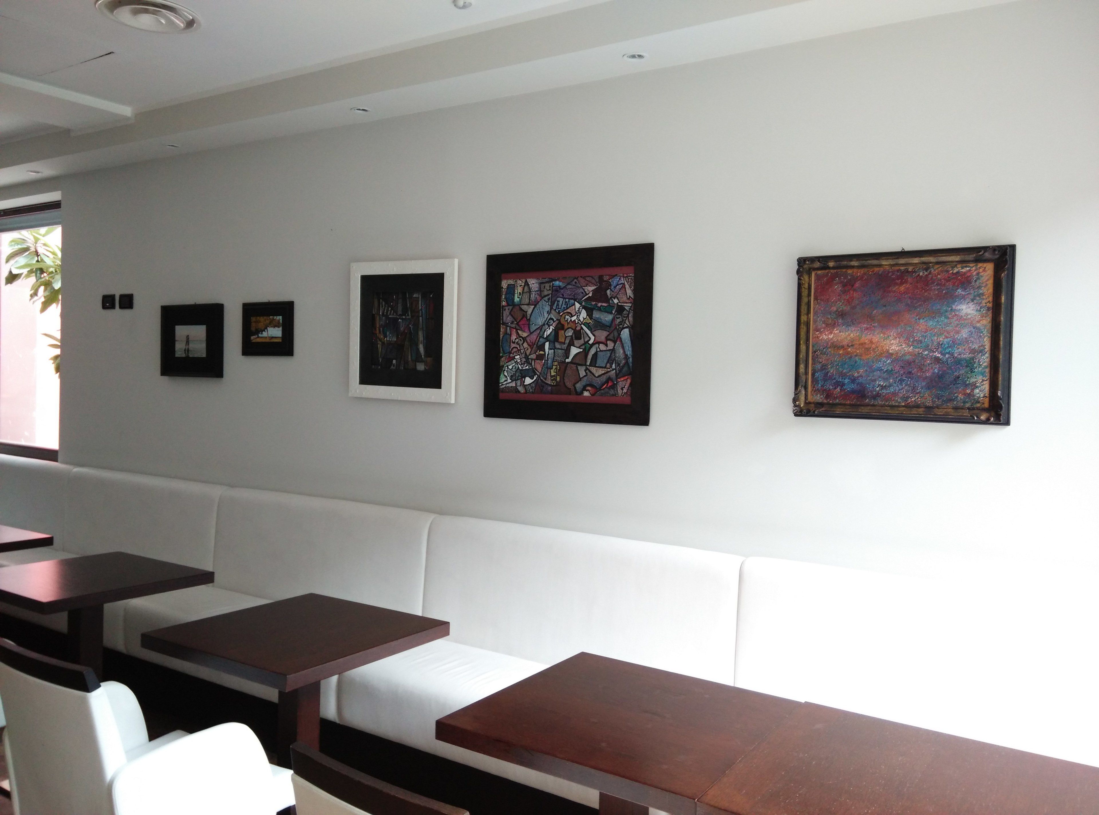 A modern interior with a white couch, wooden tables, and a wall adorned with framed artworks.