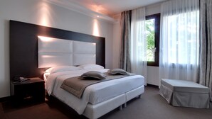 A modern hotel room with a large bed, bedside table, and a small bench. - Hotel Villa Pannonia (Venice)
